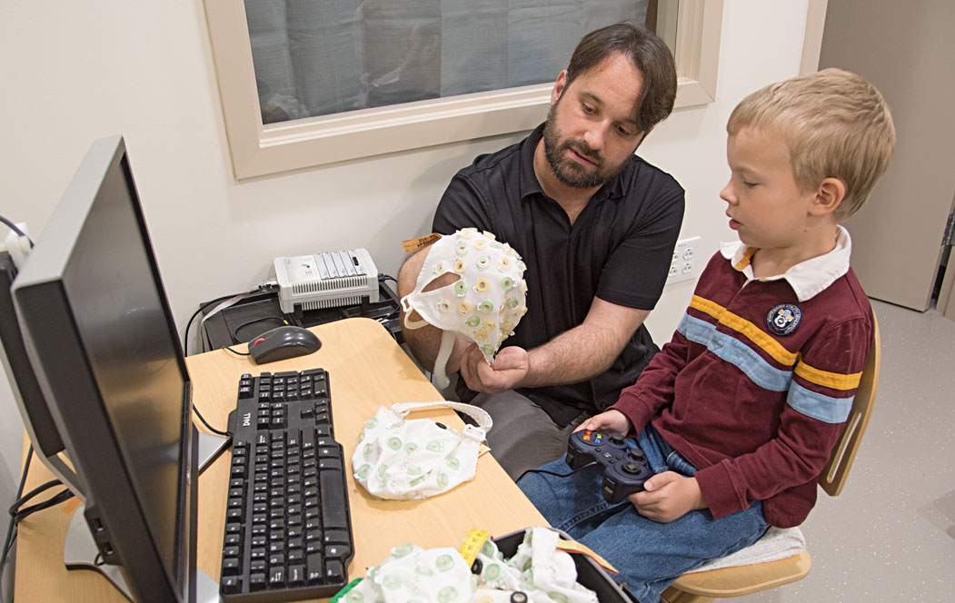 Study first author Andy C. Belden, PhD, explains one of the assessment tools. This caplike device makes it easier to measure brain electrical activity in young children.
